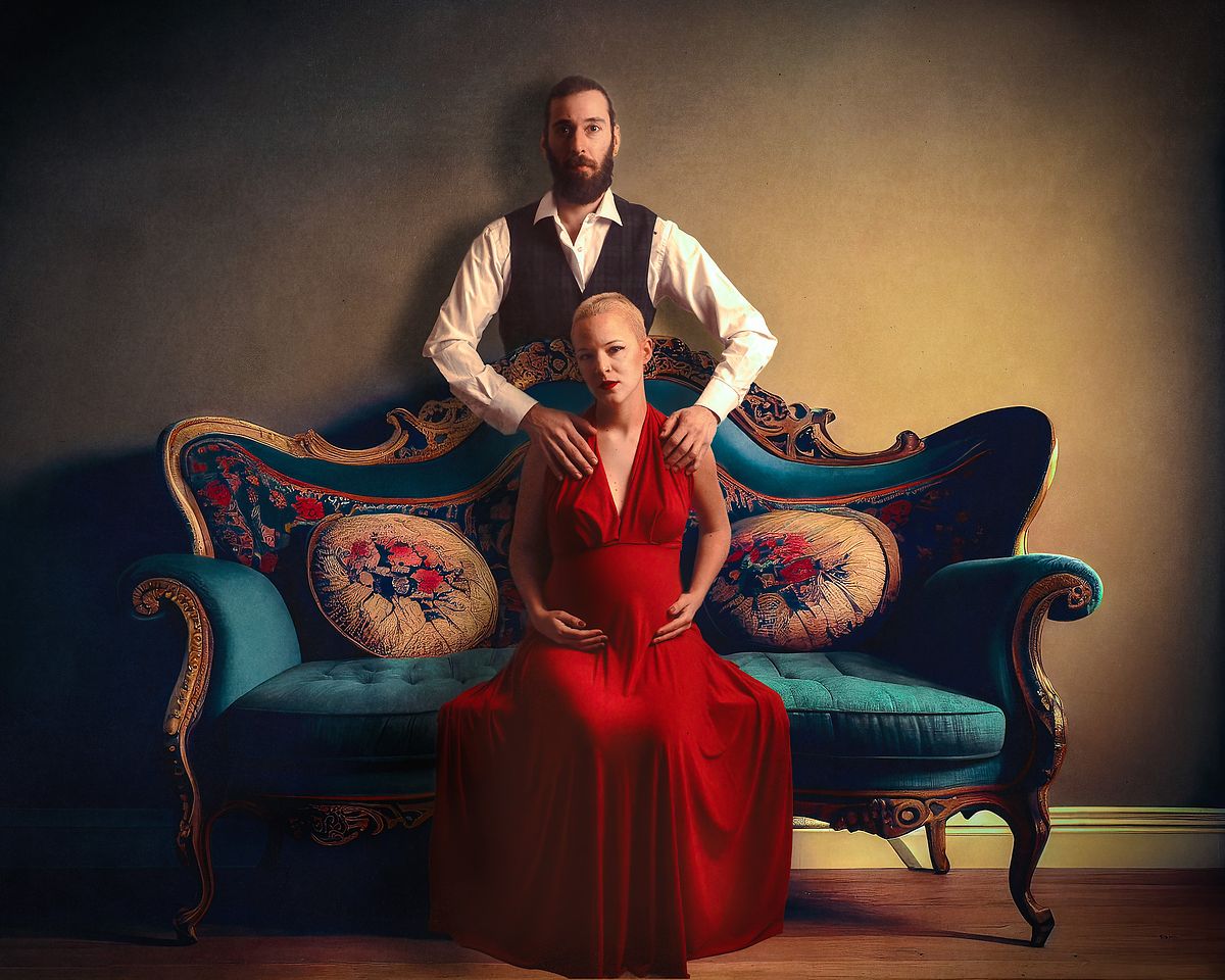 photo tarot couple attendant un enfant, femme en robe rouge et homme debout derri&egrave;re elle, atmosph&egrave;re solennelle et intime