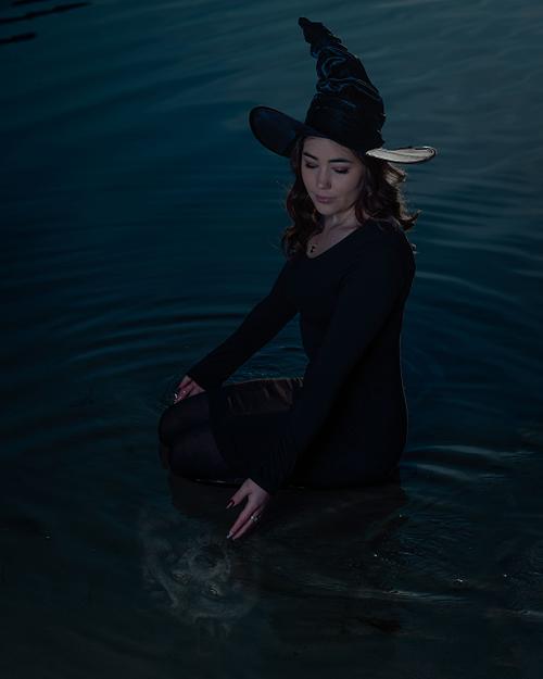 A witch looks at her wolfy reflection in the lake water.