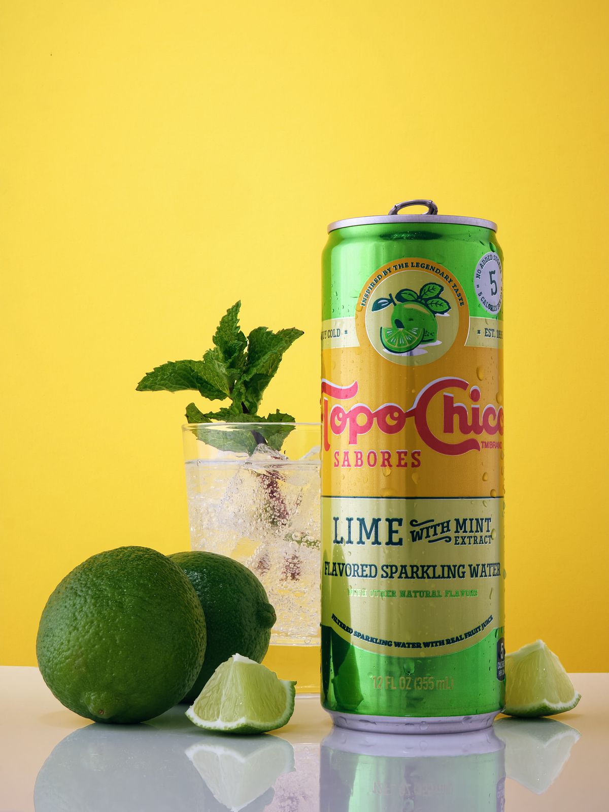 Lime seltzer can beside a mint garnished glass and limes.