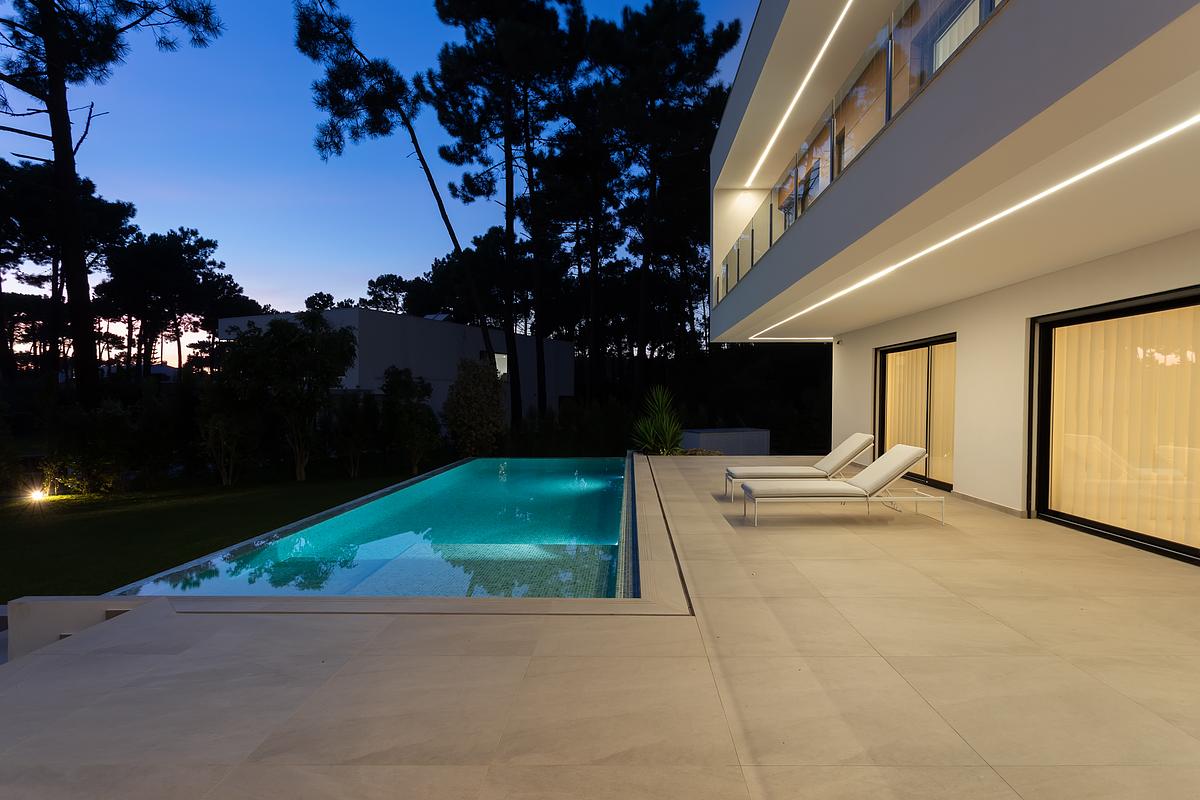 Fotografia de moradia contempor&acirc;nea na Herdade da Aroeira com piscina e ilumina&ccedil;&atilde;o noturna