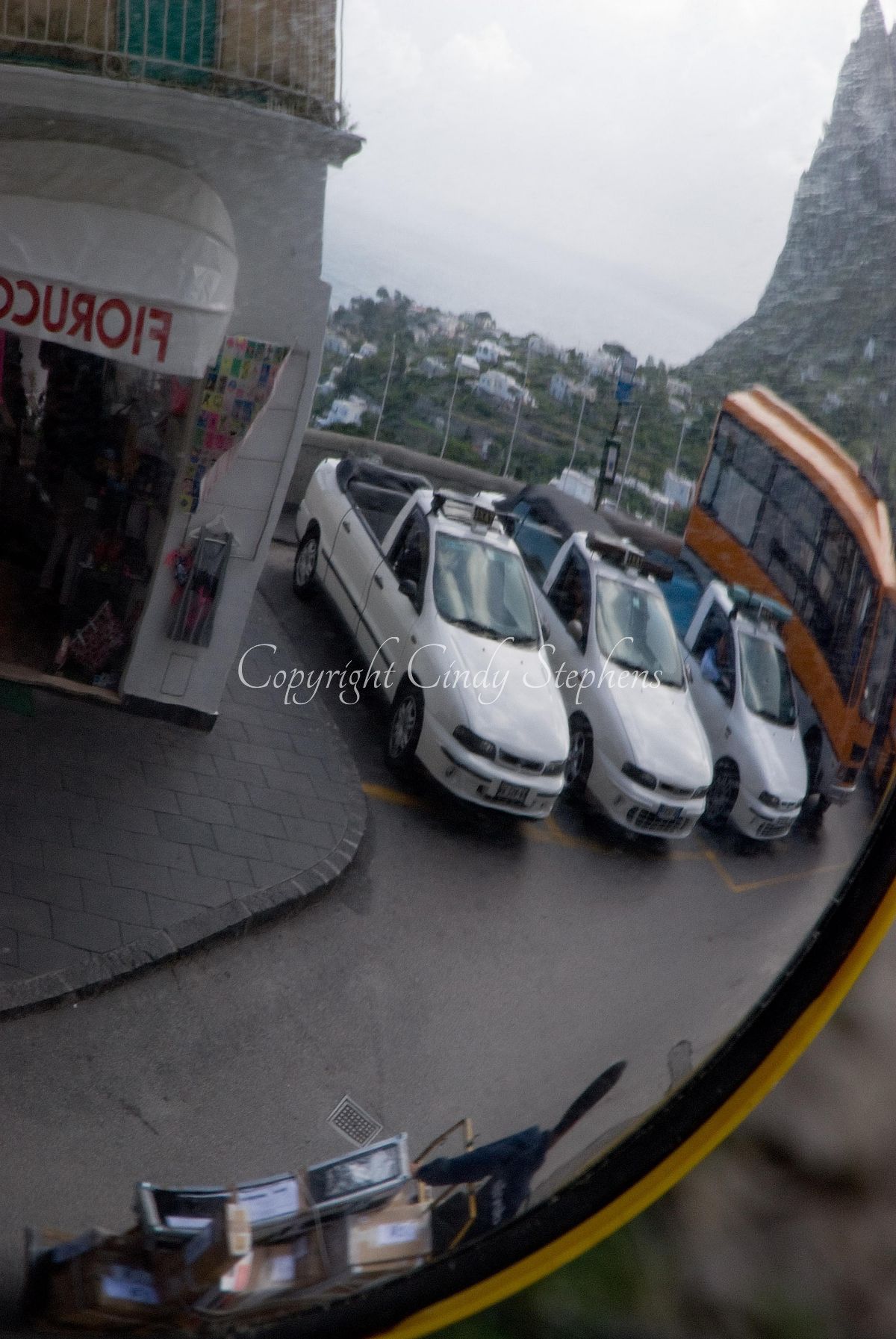Reflection of three white convertibles and a bus against a mountain backdrop in Southern Italy
